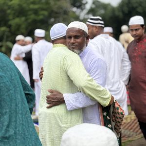বৃষ্টির মধ্যে মুসল্লিদের কোলাকুলির দৃশ্য।